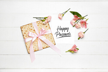 Card with text HAPPY PASSOVER, flatbread matza and alstroemeria flowers on light wooden background
