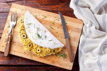 homemade tapioca or beiju stuffed with boiled chicken and olives on rustic wooden table