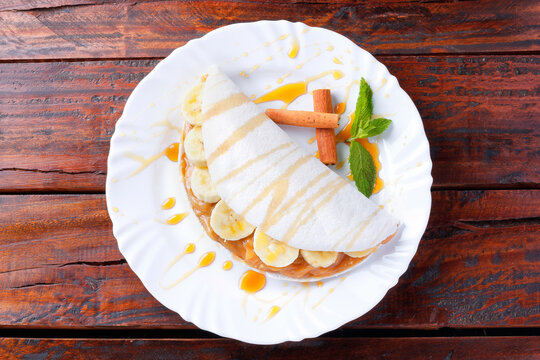 homemade tapioca or beiju stuffed with banana and condensed milk or malted caramel on rustic wooden table