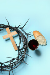 Fototapeta na wymiar Crown of thorns, cross, cup of wine and bread on blue background