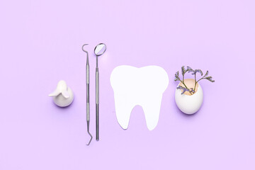 Paper tooth with dental tools, Easter rabbit, egg shell and flowers on lilac background