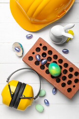 Builder's tools with Easter eggs and rabbit on white wooden background