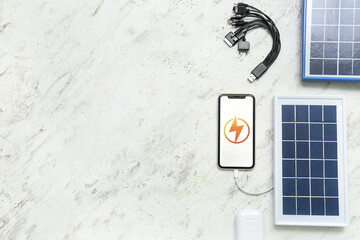 Portable solar panel charging mobile phone on white grunge background