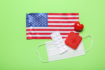 Medical mask, pills, heart and USA flag on green background