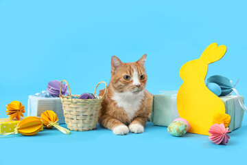 Fototapeta na wymiar Cute cat with Easter eggs, gifts and paper rabbit on blue background
