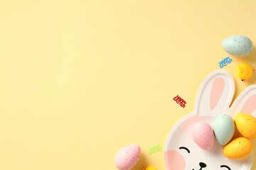 Happy Easter banner design. Bunny shaped plate with colorful Easter eggs on pastel yellow background.