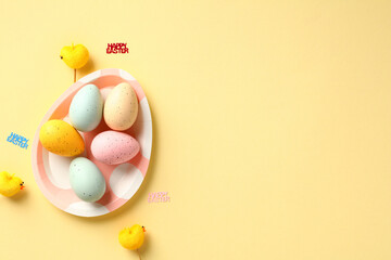 Happy Easter greeting card template. Flat lay colorful Easter eggs on plate on yellow background.