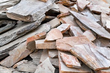 Heap of natural brown stone fragments for facing walls and laying paths