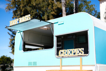 Blue and white caravan transformed into food truck with hot dog and crepe signs