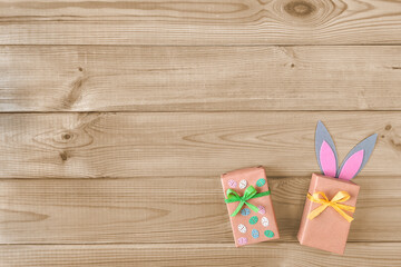 Decorating gifts for Easter. Copyspace. Top view. Concept of Happy Easter, preparation for religious holiday.  Two boxes with gifts with Easter decor on wooden background. Flat lay. Place for text