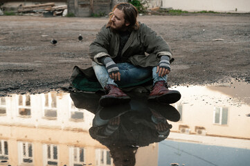 a homeless man is sitting in a puddle