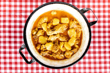 homemade chicken stew with tomato, onion and potato on checkered tablecloth