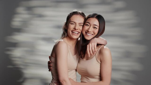 Happy diverse friends posing in studio for campaign, advertising self confidence and wellness products. Smiling girls with different skintones promoting diversity and body positivity.