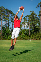 Youth male football player leaping up to make a spectacular catch 