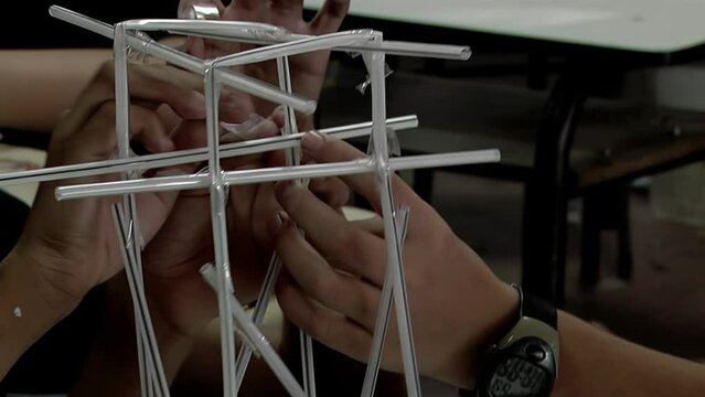 Hands of Male Secondary Students Working on a School Project Using Drinking Straws in Class. Close Up.