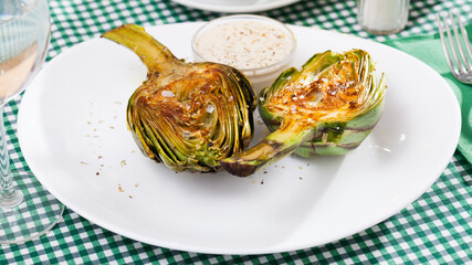 Delicious fried artichoke halves with coarse salt on a white plate. High quality photo