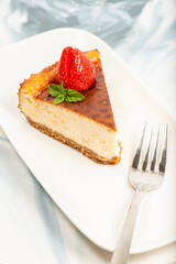 Creamy New York Cheesecake topped with fresh flowers, mint leaves, and strawberries.