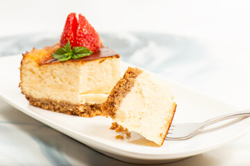 Creamy New York Cheesecake topped with fresh flowers, mint leaves, and strawberries.