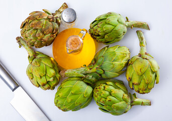 Obraz premium Bottle of vegetable oil and fresh ripe artichokes on a white background. Ingredients for cooking