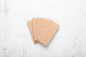 Fresh crunchy rye crispbreads on white textured table, top view