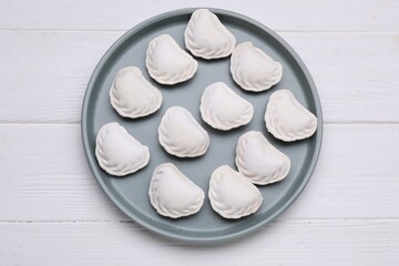 Fototapeta na wymiar Raw dumplings (varenyky) on white wooden table, top view