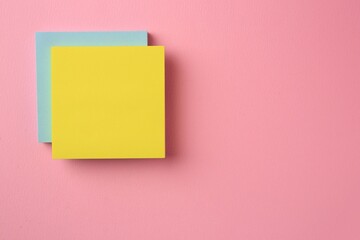 Blank paper notes on pink background, top view. Space for text