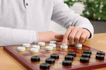 Playing checkers. Senior man thinking about next move at table in room, closeup