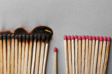 Burnt and whole matches on light grey background, flat lay