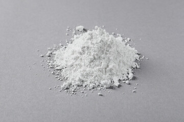 Heap of calcium carbonate powder on light grey table, closeup