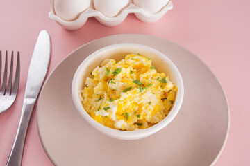 Scrambled eggs on bowl, delicious meal, pink background