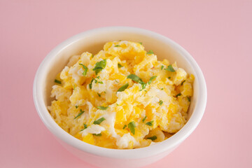 Scrambled eggs on bowl, isolated, pink background