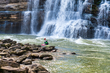 A man in a whitewater kayak, kayaking the Caney Fork River under The Twin Falls at Rock Island...