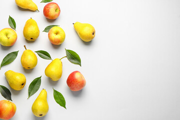 Composition with ripe pears, apples and green leaves on light background