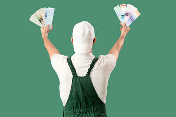Male painter with color palettes on green background, back view
