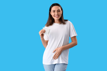 Young woman with menstrual pad on blue background