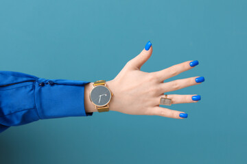 Woman with golden wristwatch on blue background