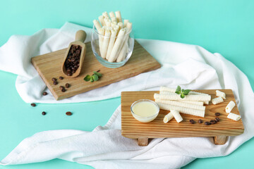 Boards with delicious wafer rolls, coffee beans and condensed milk on turquoise background