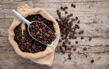 Background of dark roasted coffee beans with scoops setup on wooden background with copy space.