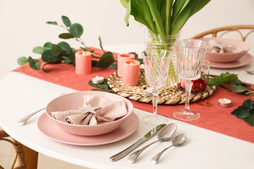 Setting for International Women's Day celebration with burning candles and eucalyptus branches on table