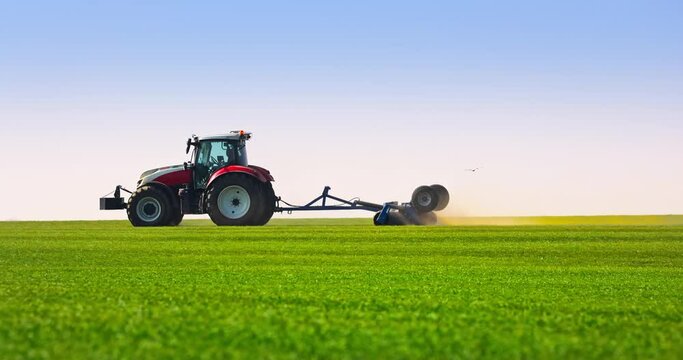 Tractor with a roller tillage working on fresh green spring field, 4k video. Soil rolling supports germination and is the basis for good harvesting