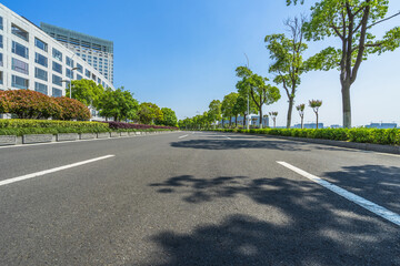 Asphalt road and green trees in the blue sky.