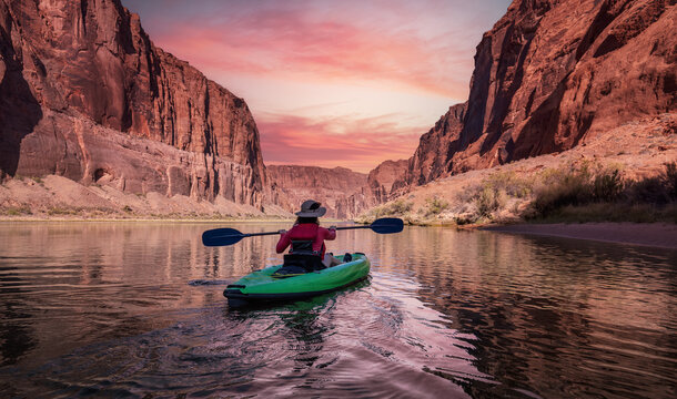 Adventurous Woman on a Kayak paddling in Colorado River. Glen Canyon, Arizona, United States of America. Sunrise Sky Art Render. American Mountain Nature Landscape Background.