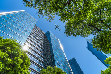 Tall city buildings and a plane flying overhead.