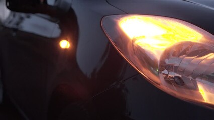 Detail of a black car with yellow front turn signal on