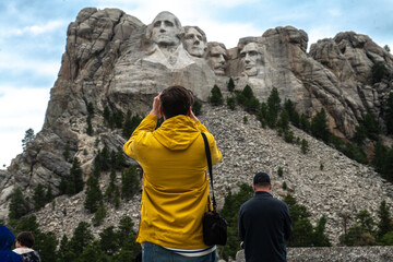 Tourists taking pictures and observe mountain Rushmor with USA presidents sculptures - obrazy, fototapety, plakaty