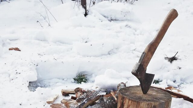 a shovel throws snow next to an ax in a stump, slow motion, close-up