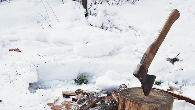a shovel throws snow next to an ax in a stump, slow motion, close-up