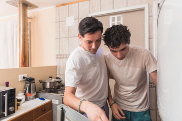 Young gay couple in pajamas looking inside the fridge to prepare breakfast in the morning.