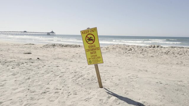 Keep Out Sewage Contaminated Water Beware Sign on Imperial Beach California sunny day - slow motion with pier