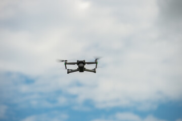 Drone flying in a blue sky, The grey unmanned aerial vehicle on cloudy sky background.